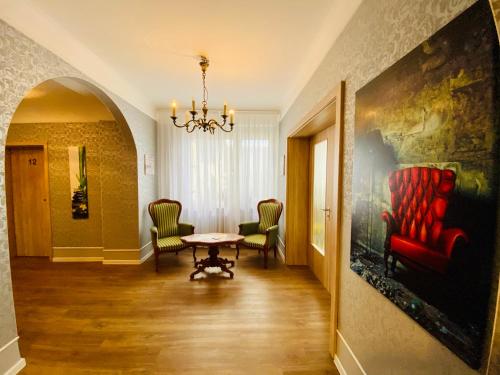 a living room with a table and chairs and a painting at Gästehaus am Kurpark Hotel Garni in Horn-Bad Meinberg