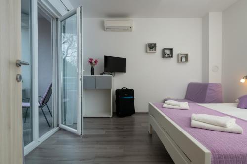 sypialnia z łóżkiem i przesuwnymi szklanymi drzwiami w obiekcie Apartments Greta & Ivona w Puli
