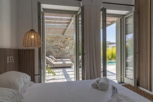 - une chambre avec un lit et une porte coulissante en verre dans l'établissement Cove Paros, à Náoussa