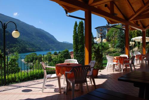 a patio with tables and chairs and a view of a lake at Charme Hotel Nevada in Molveno