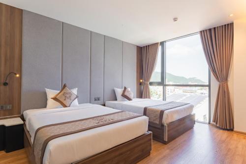 a hotel room with two beds and a large window at MERIA Hotel Quy Nhơn in Quy Nhon