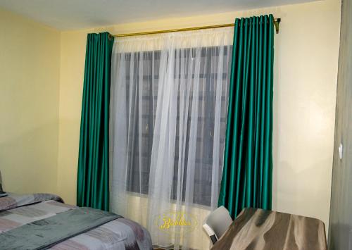 a bedroom with green curtains and a window at Bubbles Lodge Kinangop in South Kinangop