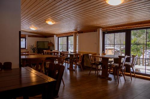 a dining room with tables and chairs and windows at Chata Myšák in Malá Morávka