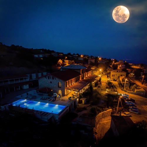 a view of a town at night with a full moon at Assos Sunaba Kasri Hotel in Behramkale
