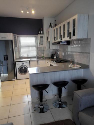 a kitchen with a counter and two bar stools at lovely 1 bedroom apartment in Ballito