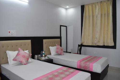a bedroom with two beds with pink pillows at Bodhi Stay in Bodh Gaya