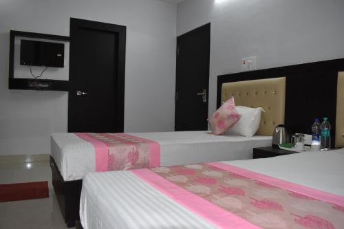 a hotel room with two beds and a tv at Bodhi Stay in Bodh Gaya