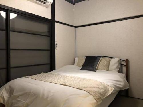 a bedroom with a white bed with a black headboard at ゲストハウス扇 in Takamatsu