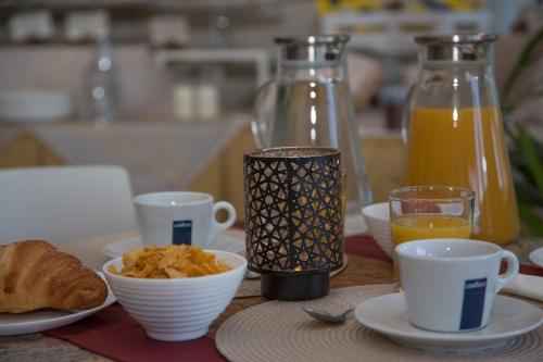 a table with cups and plates of food and orange juice at Hotel Chalet del Lago in Avigliana
