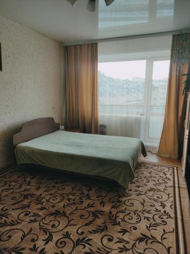 ゴルノ・アルタイスクにあるApartment on Kommunisticheskiy prospekt 92のベッドルーム1室(ベッド1台、大きな窓付)