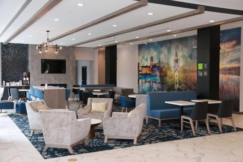 a lobby with tables and chairs and a painting at LaQuinta Suites by Wyndham South Bend Notre Dame Area in South Bend