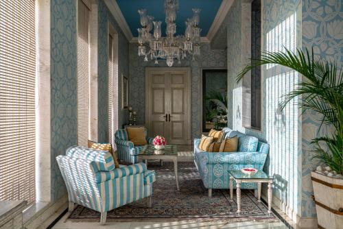 a hallway with two blue chairs and a chandelier at Rajmahal Palace RAAS in Jaipur