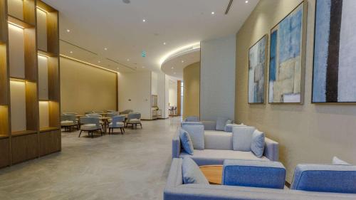 a waiting room with blue couches and tables and chairs at Clarion Hotel Jeddah Airport in Jeddah