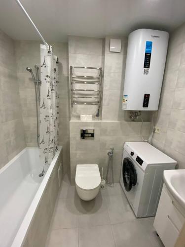 a bathroom with a toilet and a washing machine at Замечательная евродвушка район Теремков 209 in Teremki