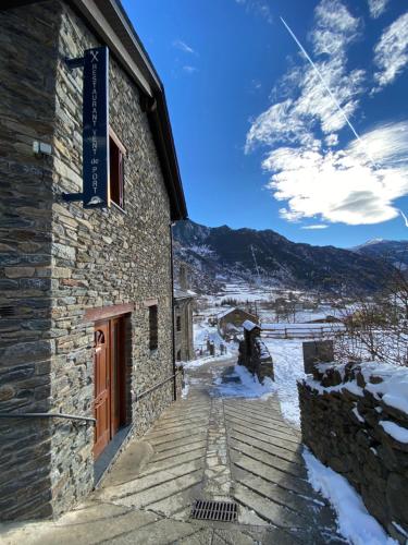 a building with snow on the ground next to a mountain at Aparthotel Areu in Areu