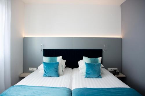 a bedroom with a large bed with blue and white pillows at Colmar Hotel in Colmar