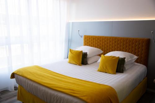 a bedroom with a large bed with yellow pillows at Colmar Hotel in Colmar