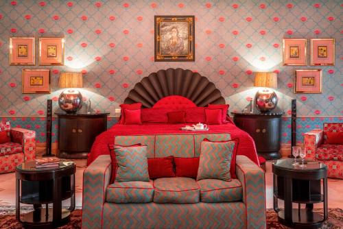a bedroom with a red bed and a couch at Rajmahal Palace RAAS in Jaipur