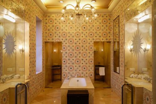 a bathroom with two sinks and a chandelier at Rajmahal Palace RAAS in Jaipur