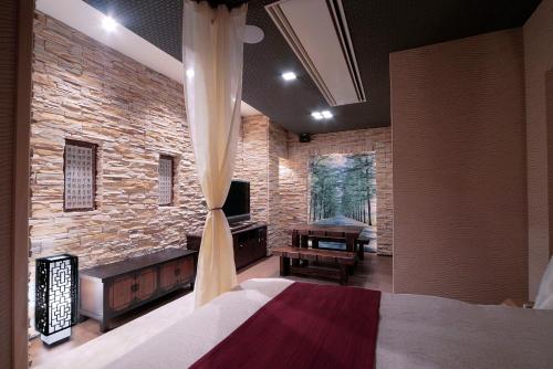 a bedroom with a stone wall and a bed and a television at ホテル隠宿 凛 Rin in Ogaki
