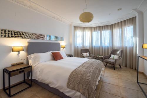 a bedroom with a large white bed and chairs at La Rayuela in Monachil