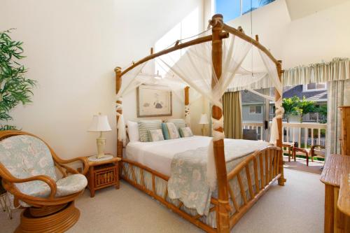 a bedroom with a canopy bed and a chair at Regency 522 in Koloa