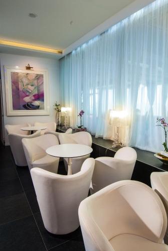 a waiting room with white chairs and tables at Hotel Mediterraneo in Riccione