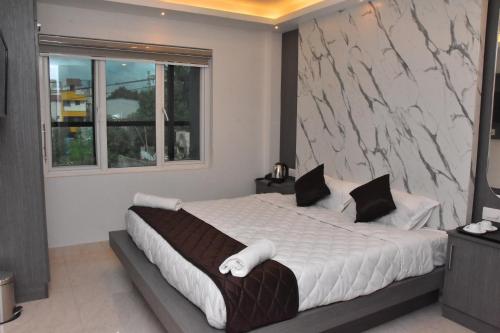 a bedroom with a large bed with a marble wall at Sanns Tropicana in Chennai