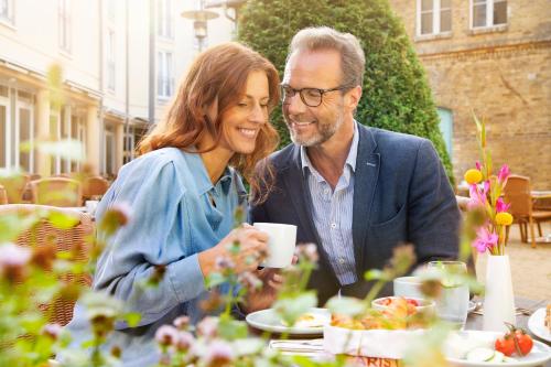 a man and woman sitting at a table eating food at MAXX Hotel Sanssouci Potsdam in Potsdam