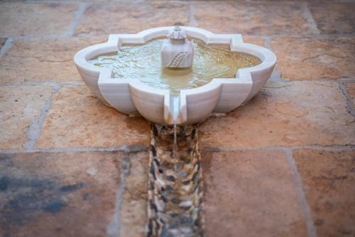 a bird bath sitting on a brick floor with a birdbathificialificialificialificial at La Rayuela in Monachil