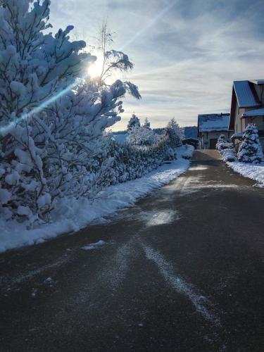 a road covered in snow with the sun in the background at Apartamenty Równia 2 in Ustrzyki Dolne