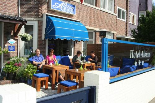 a group of people sitting at tables outside a restaurant at Hotel Albion in Scheveningen