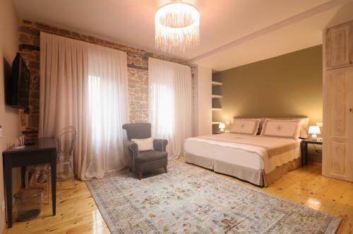 a bedroom with a bed and a chair and a chandelier at Në Kroi in Korçë