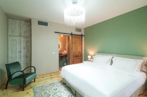 a bedroom with a large white bed and a green wall at Në Kroi in Korçë