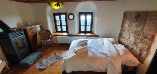 a bedroom with a bed and a fireplace and two windows at Archontiko Mansion Porteli Αρχοντικο Πορτελι in Makrinítsa