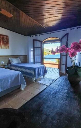 a bedroom with two beds and a view of the ocean at Pousada Três Coqueiros in Praia do Bananal