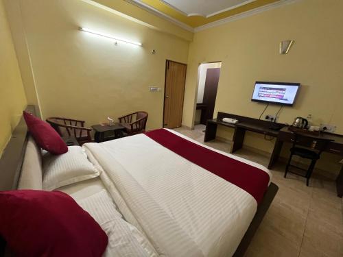 a bedroom with a bed and a desk and a television at Hotel Magnet House in Dehradun