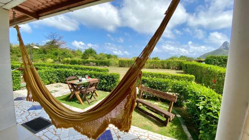 a hammock on a patio with a table and chairs at FLAT BAÍA DO SANCHO in Fernando de Noronha
