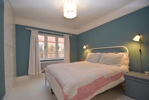 a blue bedroom with a bed and a window at Seaside Retreat in Rye Harbour