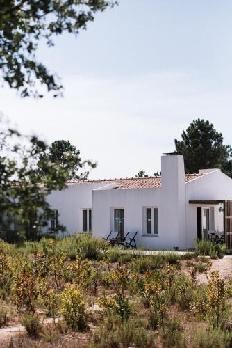 a white house in the middle of a field at Craveiral Farmhouse by Belong Staying & Feeling in São Teotónio