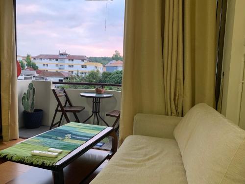a living room with a couch and a table and a window at Kiang Mo Gumpuju in Chiang Mai
