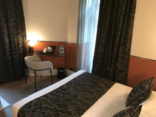 a hotel room with a bed and a chair and a desk at Le Grand Hôtel Mont Dore in Le Mont-Dore
