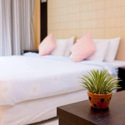 a bed with pink pillows and a potted plant on a table at ทิลแลนด์เซีย รีสอร์ท in Thanya Buri