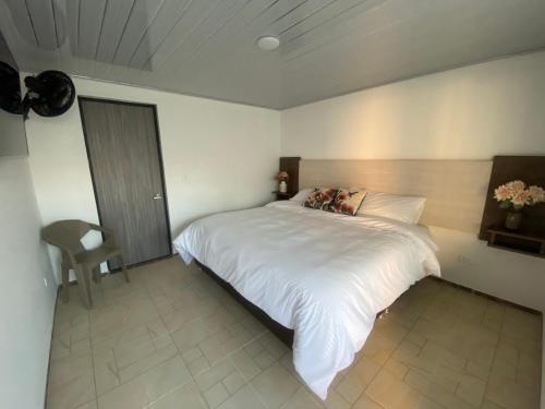 Un dormitorio con una gran cama blanca. en Hotel Celeste Inn Chinauta- Fusagasugá, en Chinauta