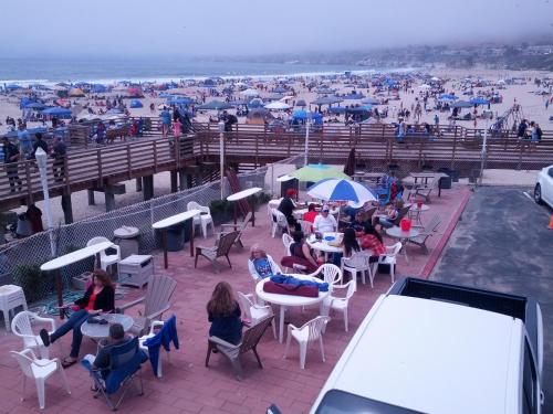 a group of people sitting at tables on the beach at Dolphin Cove Motel in Pismo Beach