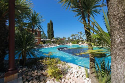 una piscina en un complejo con palmeras en La Boheme Chambres, en Lazise