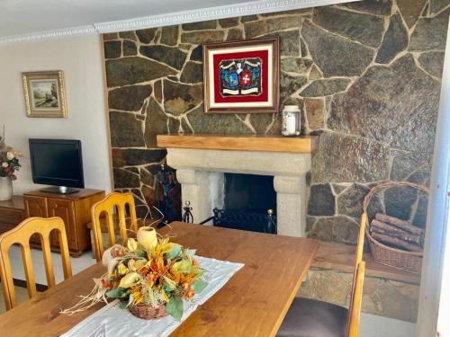 uma sala de jantar com uma lareira de pedra e uma mesa de madeira em CASA RURAL COSTALAGO em Hontoria del Pinar