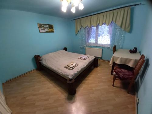 a blue room with a bed and a table at Садиба Райський Куточок in Synevyr