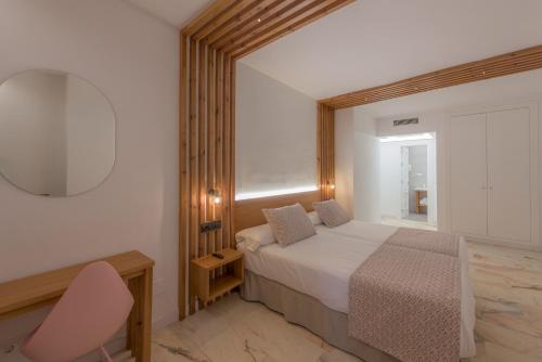 a bedroom with a bed and a chair and a mirror at Hotel Boutique Sibarys - Adults Recommended in Nerja