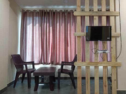 sala de estar con mesa, sillas y TV en Bliss Rooms en Alibaug